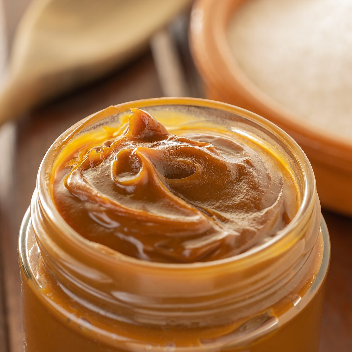 Pote de vidro aberto com doce de leite caseiro cremoso